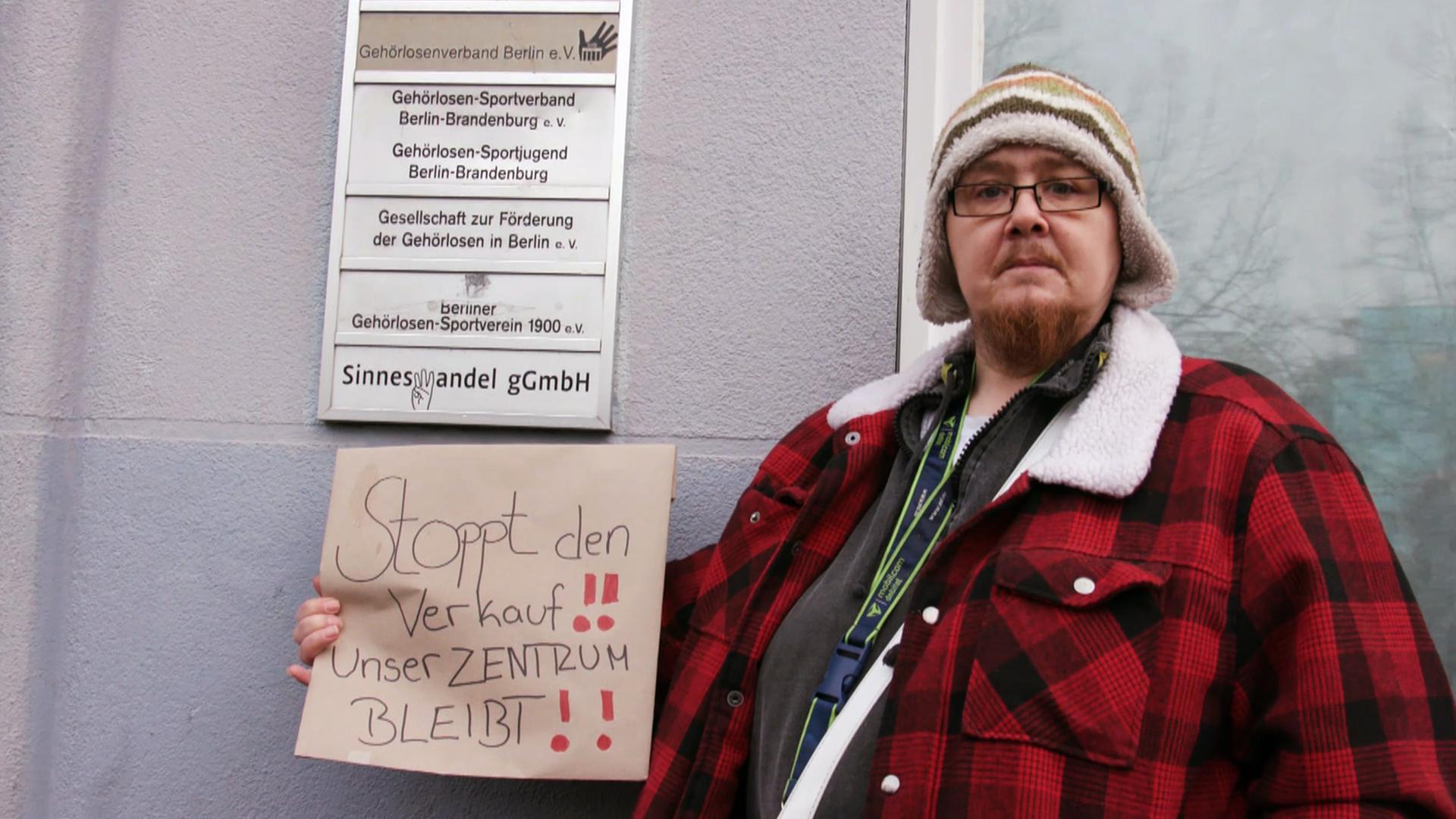 Eine Frau vor einem Schild eines gehörlosen Zentrums.