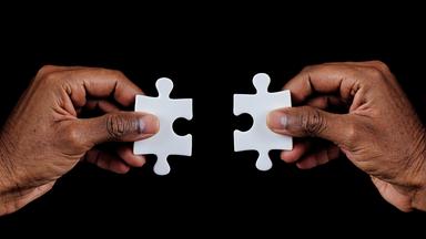 Zwei Hände, die Puzzleteile halten