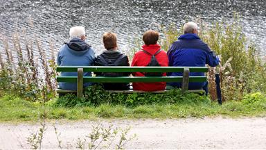 Ältere Menschen auf einer Bank am Wasser