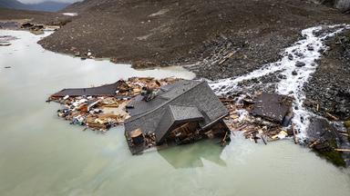 Ein teilweise verschüttetes Haus ragt aus Geröll und WasserTeilweise verschüttetes Haus ragt aus Geröll und Wasser – letzter sichtbarer Rest nach dem Gletschersturz in Blatten.