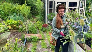 Eine Frau mit Schnittblumen in einem Garten.