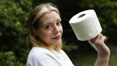 37°Leben: Müssen müssen - jung und inkontinent": Birgit, eine 40-jährige Frau mit langen blonden Haaren und einem Nasenpiercing, steht seitlich zur Kamera vor grünen Büschen. In der rechten Hand hält sie eine Rolle Toilettenpapier. Ihr Blick ist skeptisch bis fragend, dabei schmunzelt sie ein bisschen.