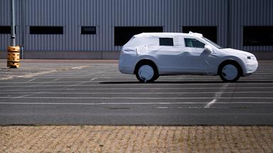 Ein einzelnes in Plane verpacktes Neufahrzeug steht auf einem Parkplatz. 