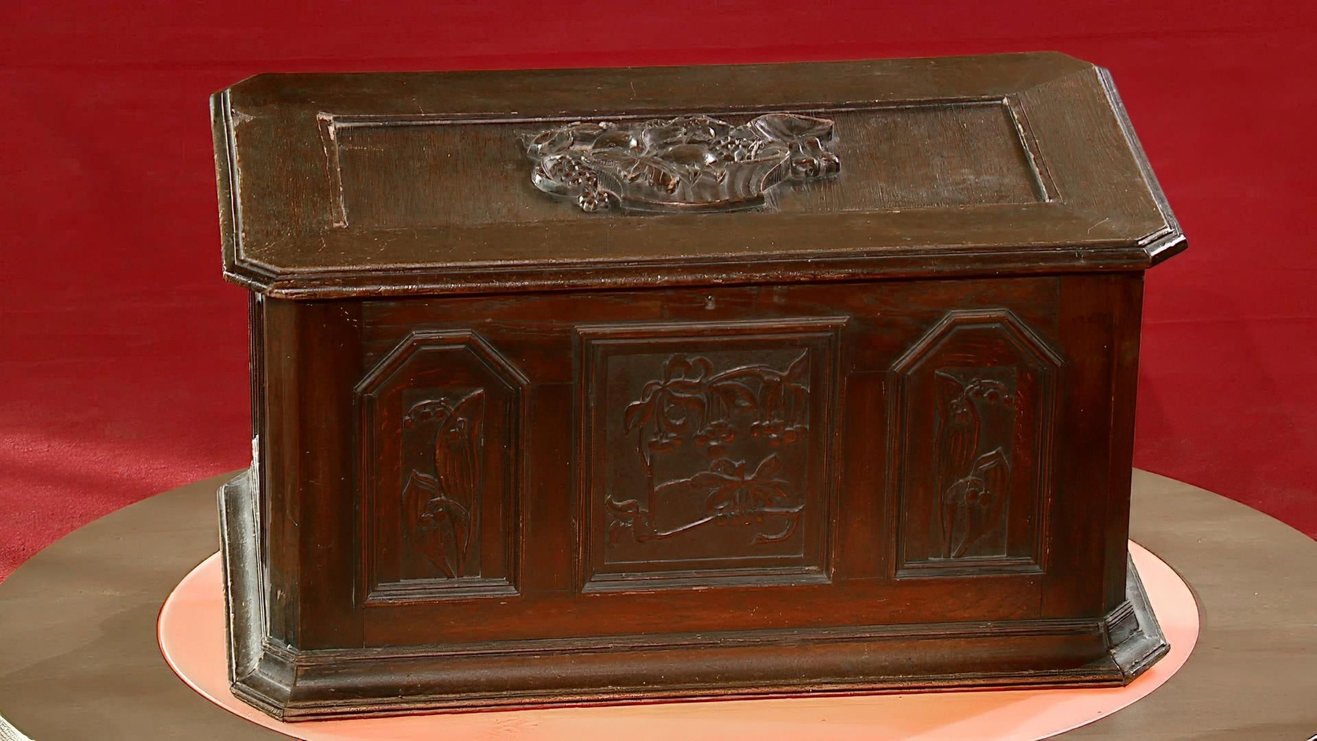 Eine Truhe mit einem seltsamen Gebäudemotiv im Deckel.