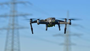 Drohne vor Strommast - Symbolbild