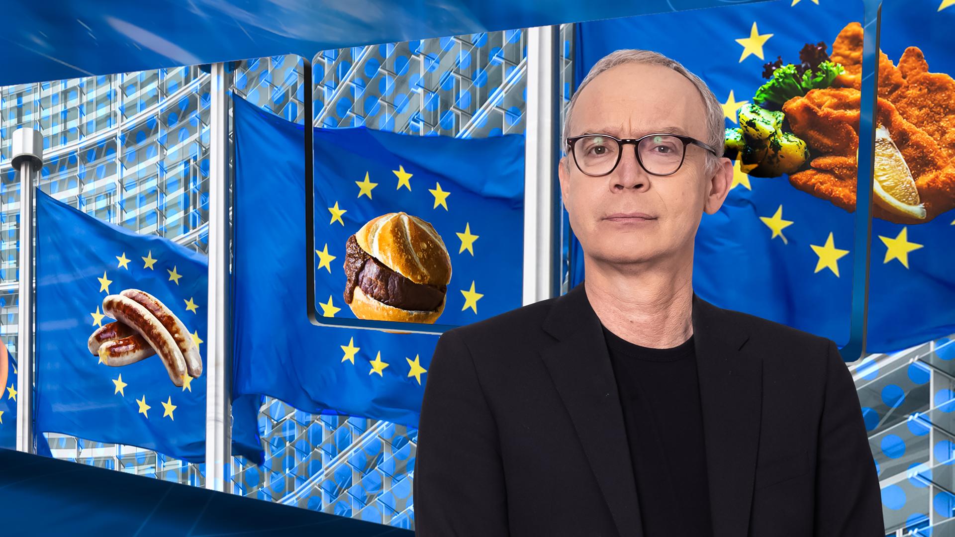 Christoph Süß vor einer Videowand, auf der mehrere gelbe Europa-Sterne zusammen mit Fleisch- und Wurstgerichten zu sehen sind.