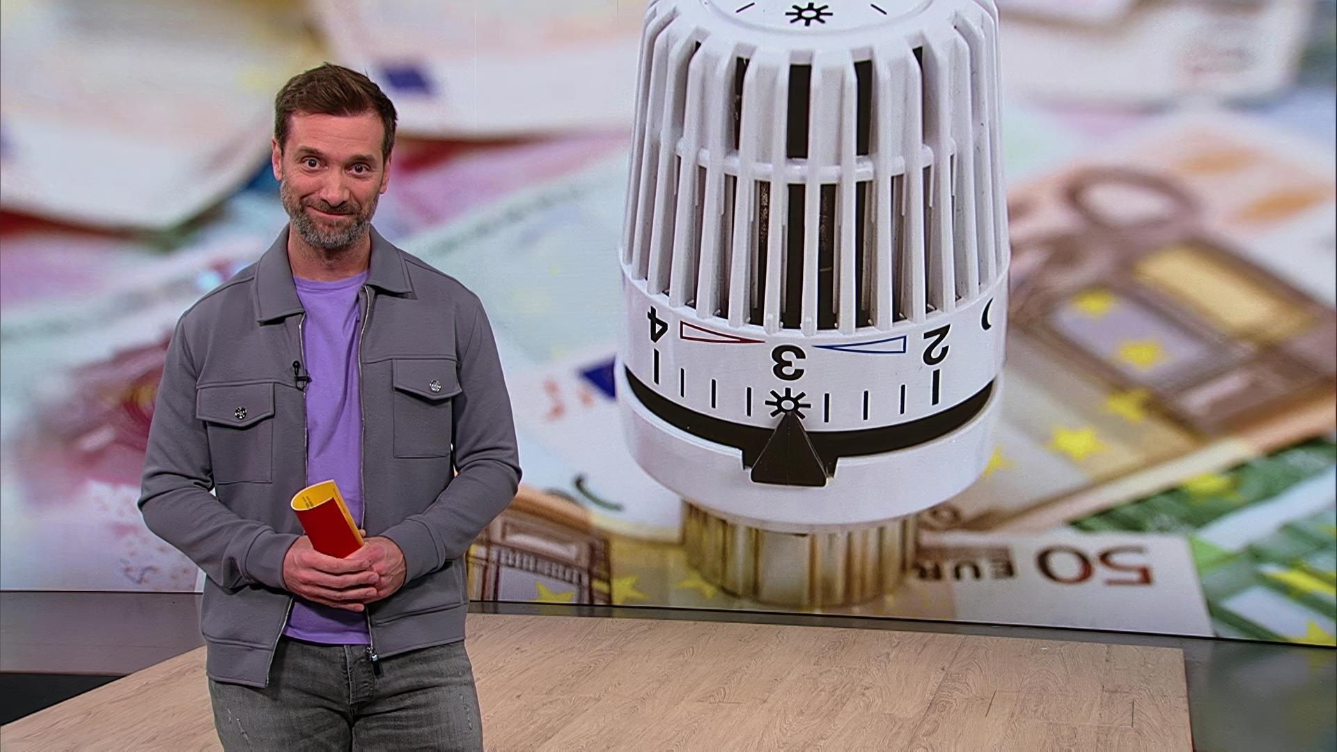 Daniel Aßmann steht im Servicezeit-Studio. Im Hintergrund sieht man die Nahaufnahme eines Heizungsreglers.