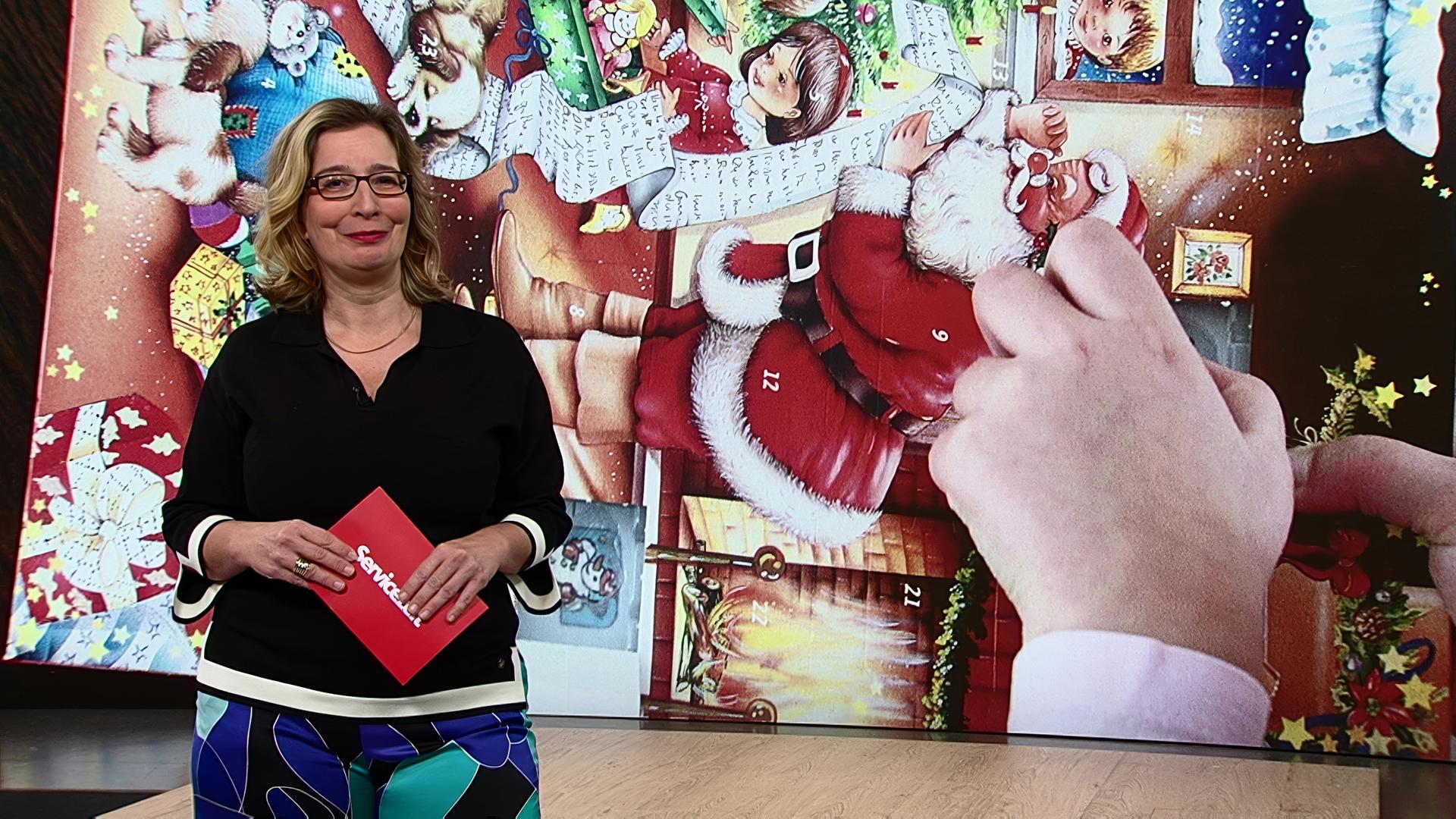 Servicezeit-Moderatorin steht im Studio. Im Hintergrund sieht man einen Adventskalender.
