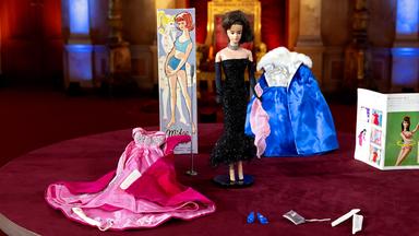 Eine alte Barbiepuppe mit Outfits.