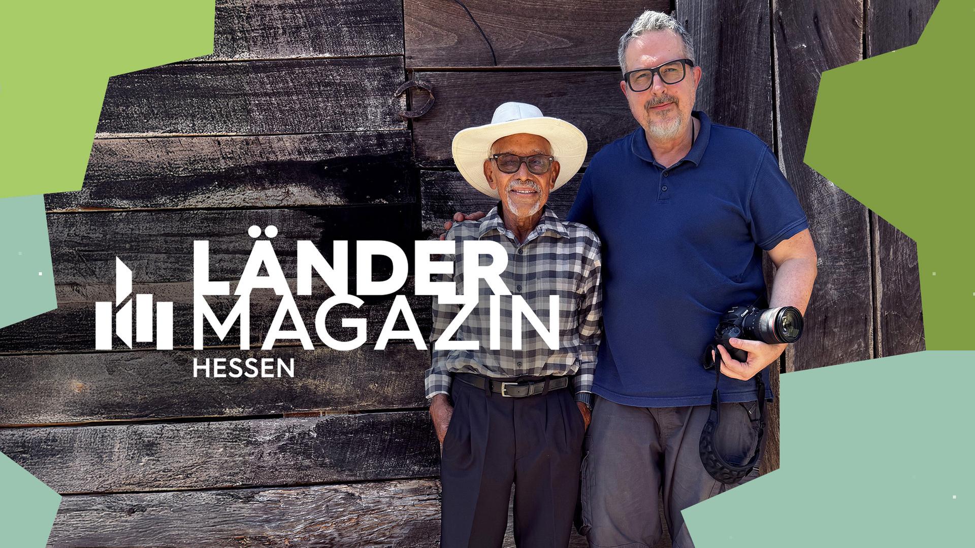 Zwei Männer vor einer Holzwand.