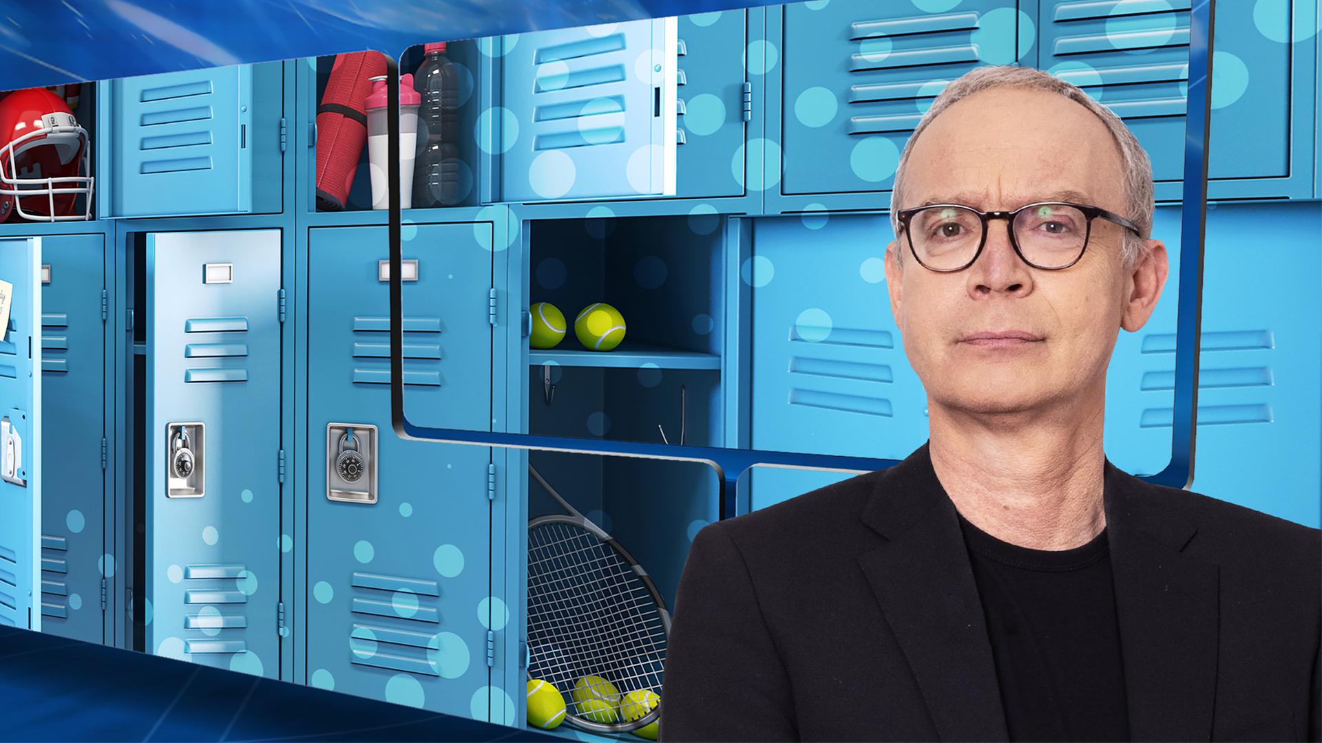 Der Moderator vor einer Videowand, auf der geöffnete Schließfächer zu sehen sind. Darin sind Tennisbälle, Getränke und ein Helm.