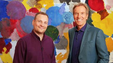 Ein jüngerer und ein älterer Mann lachen in die Kamera.