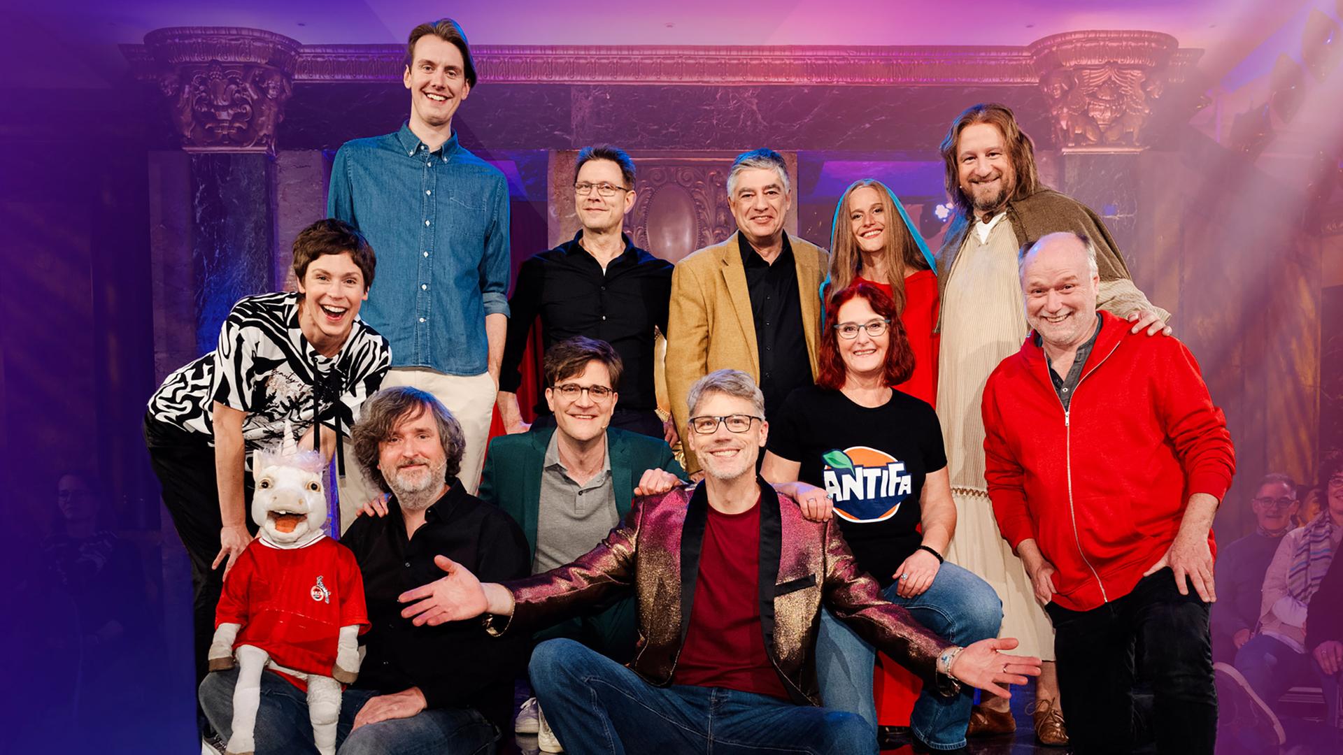 Christoph Sieber steht im roten T-Shirt auf der Bühne.