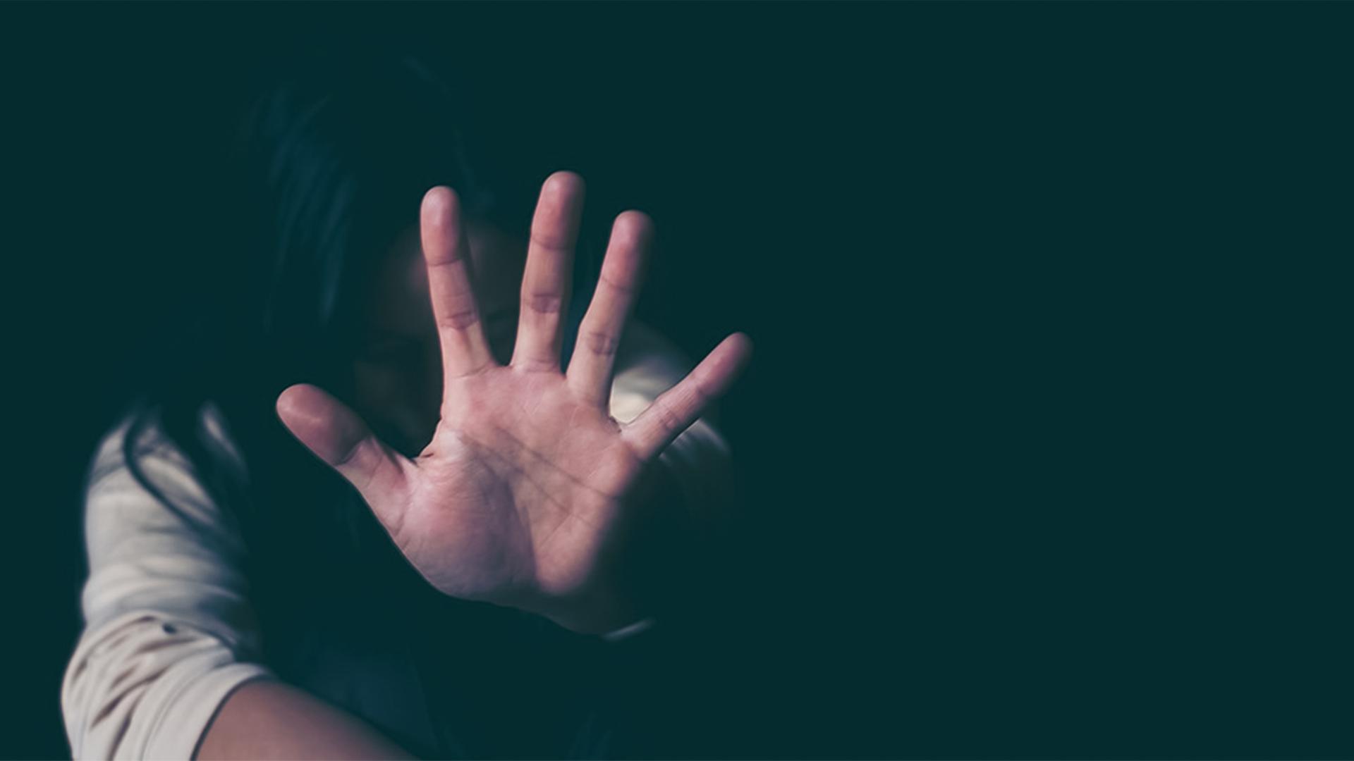 Eine Frau macht eine wehrhafte Geste, die symbolisch für Gewalt gegen Frauen steht.