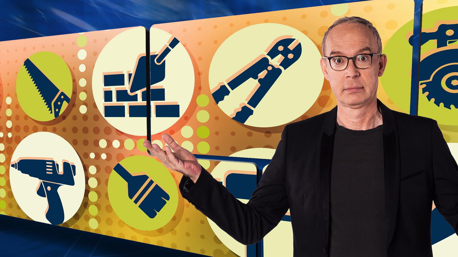 Der Moderator vor einer Videowand, auf der runde Symbolbilder von Werkzeugen zu sehen sind.
