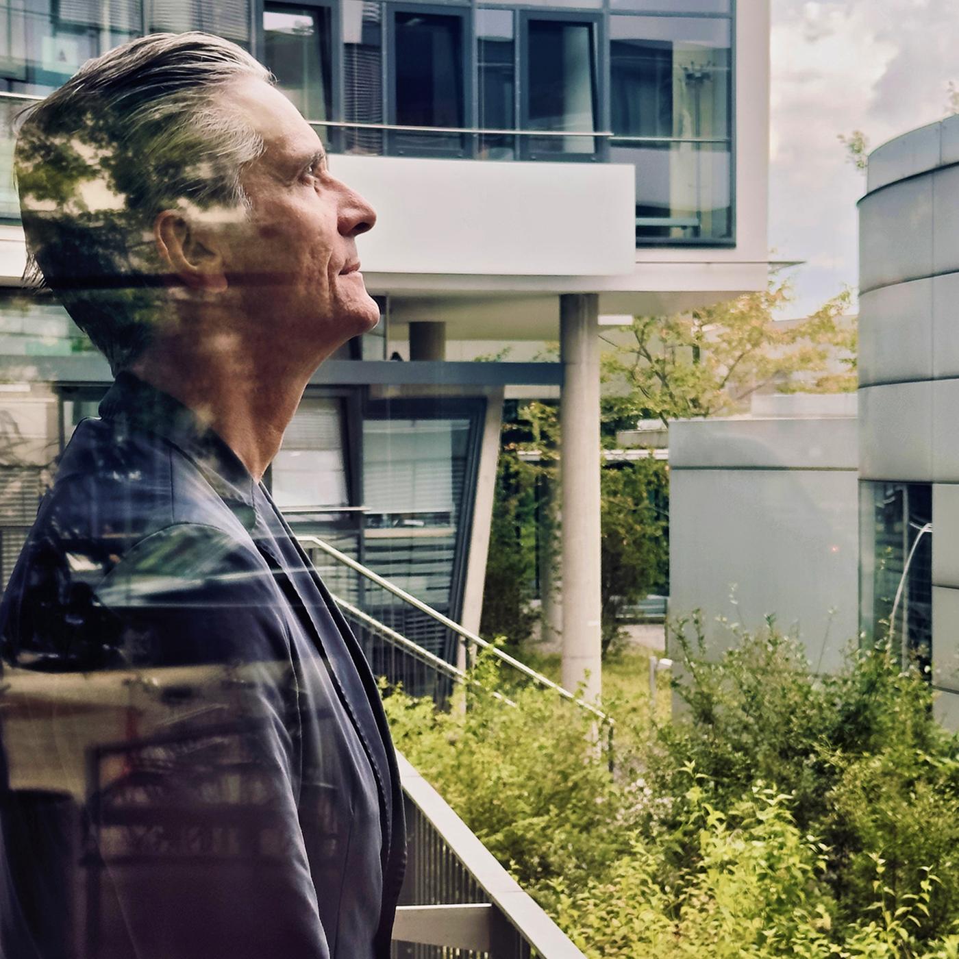 Mann steht auf einem Balkon und schaut nach oben 