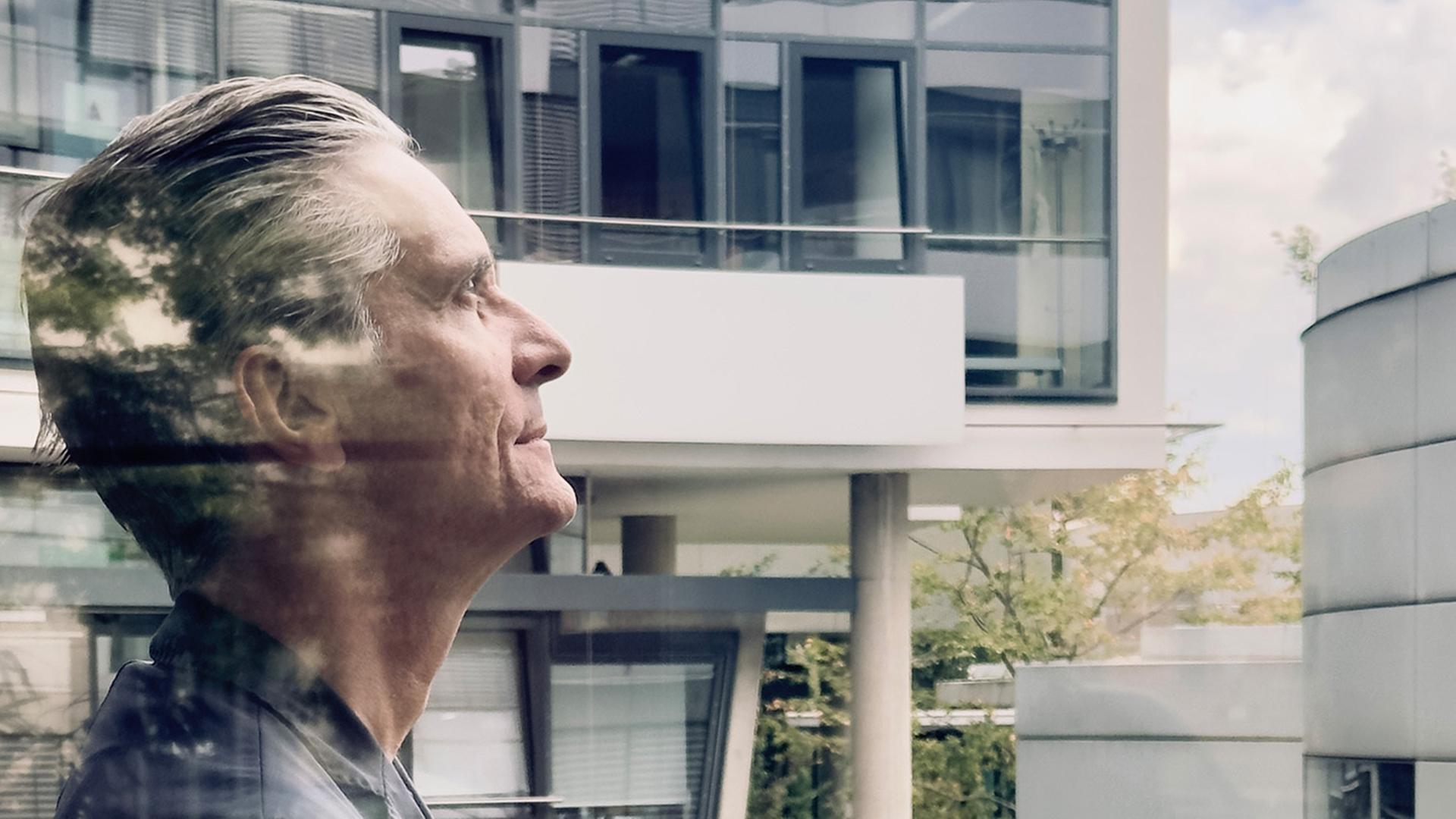 Mann steht auf einem Balkon und schaut nach oben 