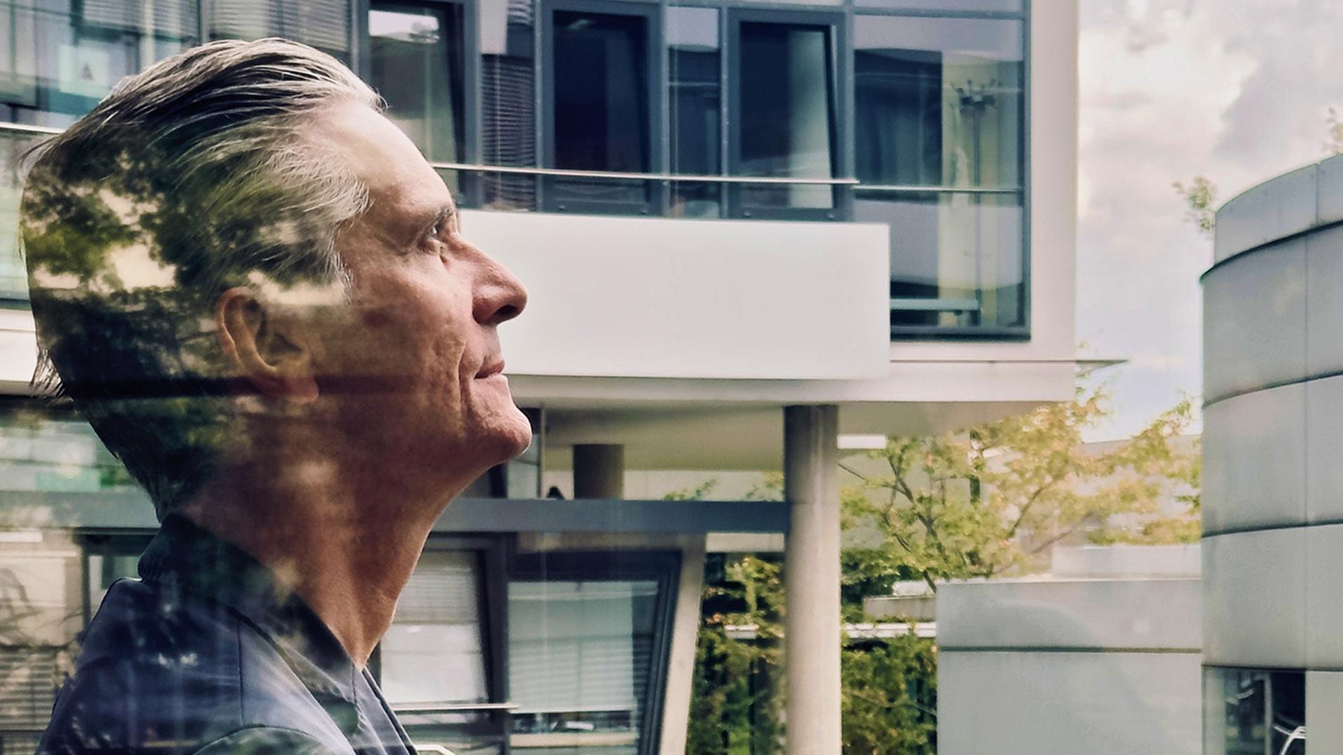 Mann steht auf einem Balkon und schaut nach oben 