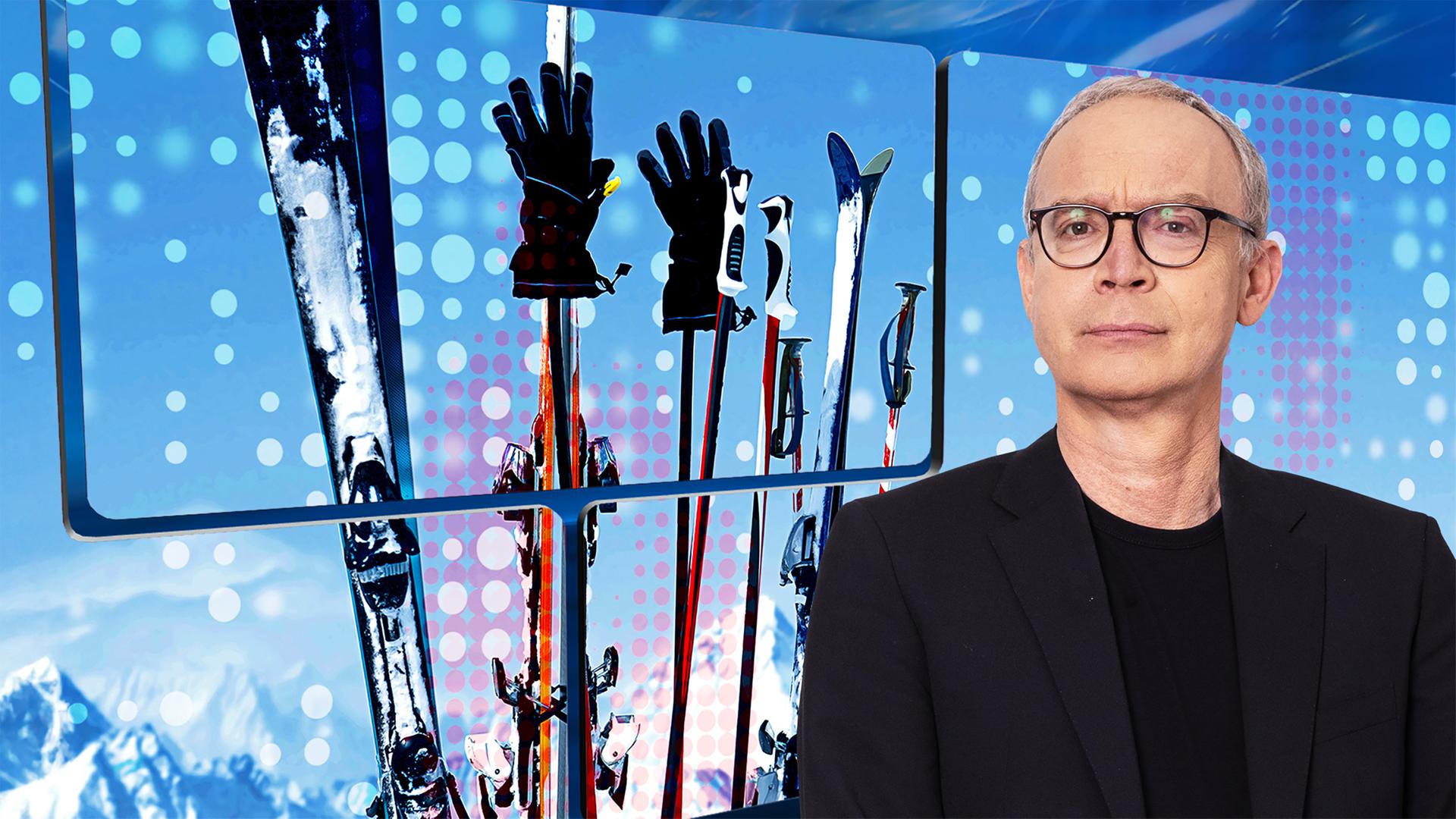 Der Moderator vor einer Videowand, auf der Ski und Skistöcke vor einem Bergpanorama zu sehen sind.