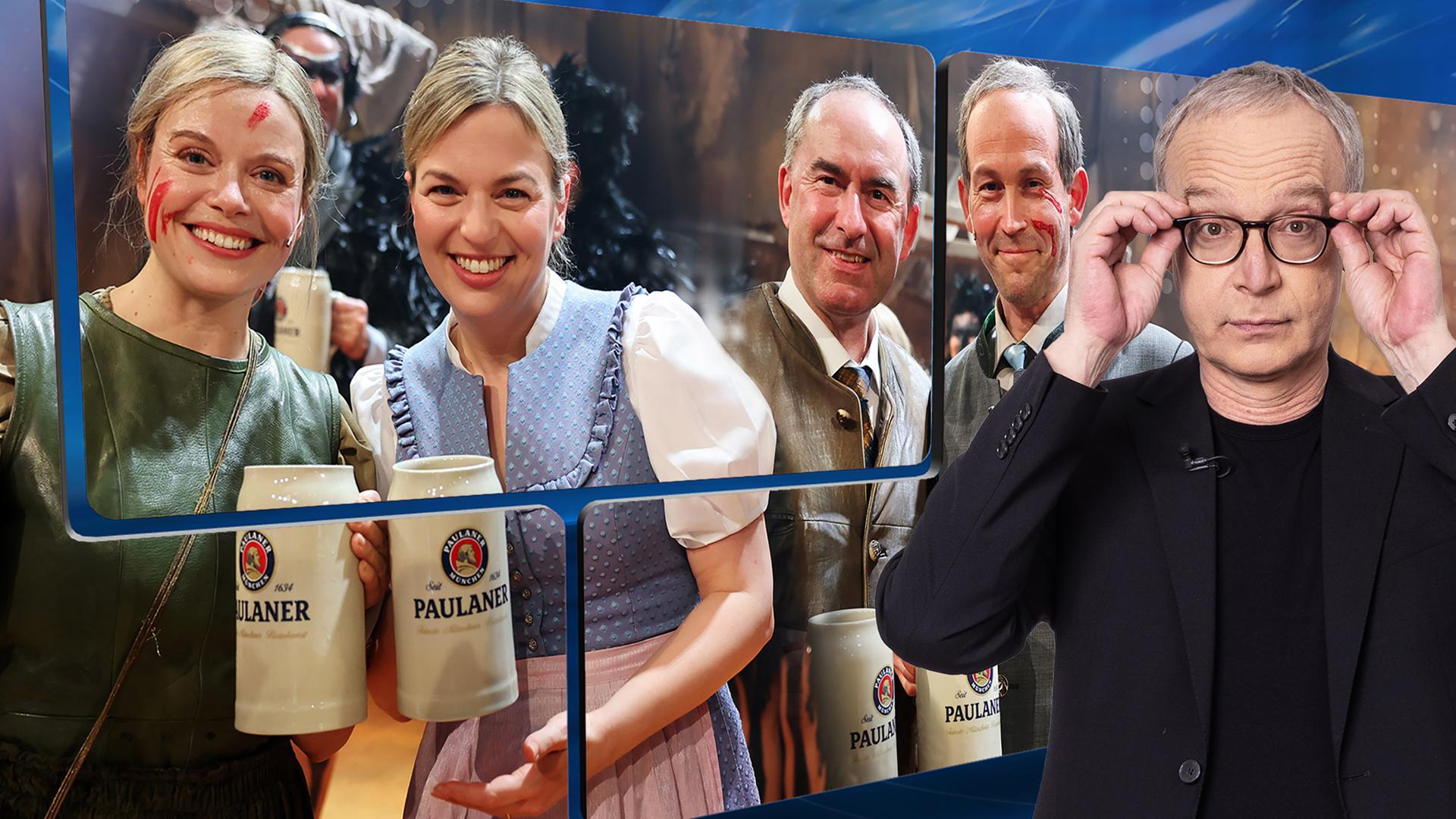 Der Moderator Christoph Süß steht vor einem Bild mit Katharina Schulze und Hubert Aiwanger und deren Schauspiel-Doublen.