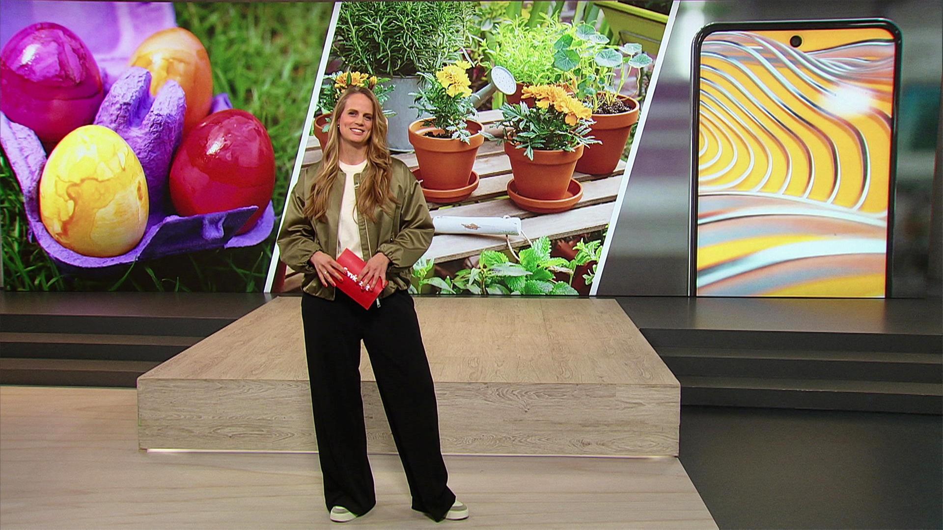 Eine junge Frau steht im Studio vor einem Hintergrundbild mit Ostereiern und Balkonpflanzen