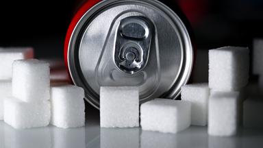 Zuckersteuer beschlosse: Dose Softdrink liegt neben Zuckerwürfeln – Symbol für Zuckergehalt und Debatte über Zuckersteuer und Ersatzstoffe.