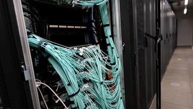 Ressourcen-Krise durch Big Tech: Jede KI-Anfrage fordert die globale Strom- und Wasserinfrastruktur in den Server-Farmen (Serverschränke mit Netzwerkkabeln sind in einem Rechenzentrum)
