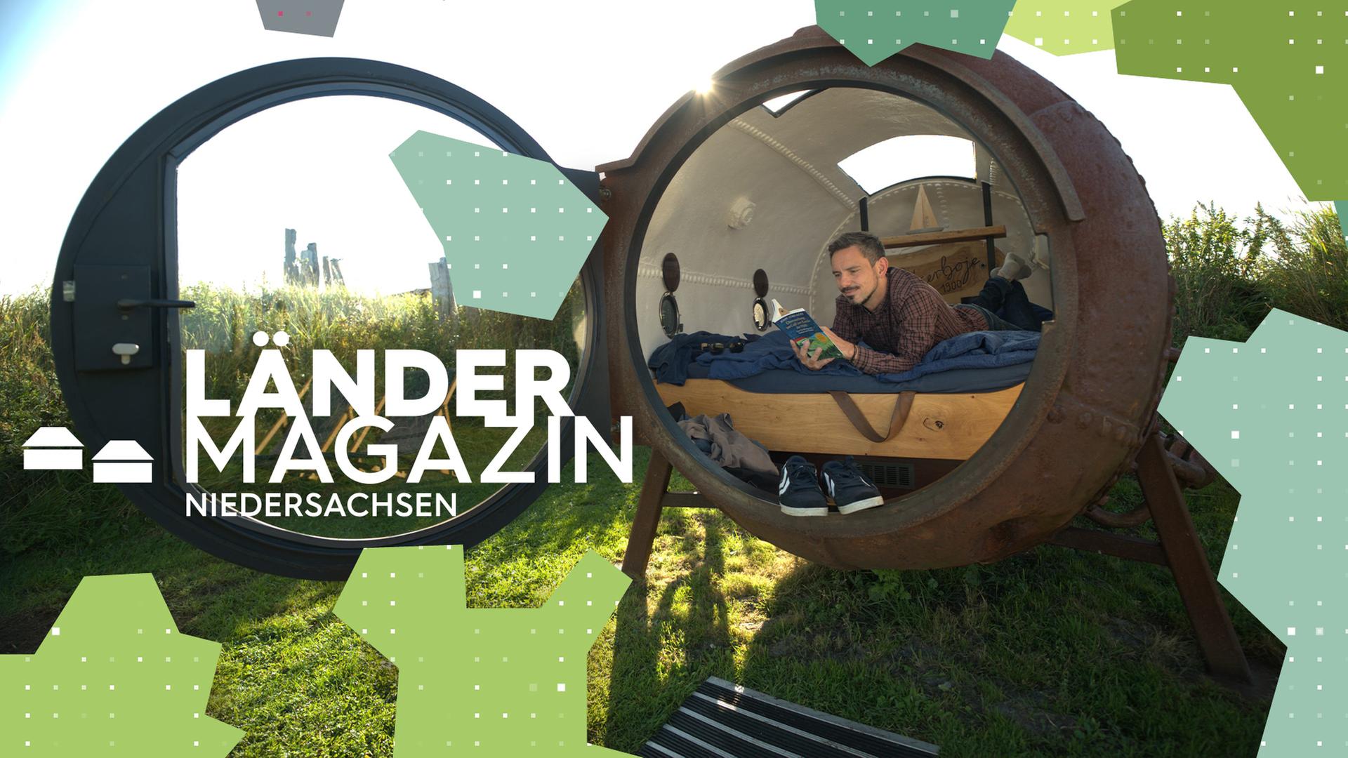 Ein Mann liegt in einem Bett, das sich in einer großen aufgeklappten Metallkugel auf einem Feld befindet.