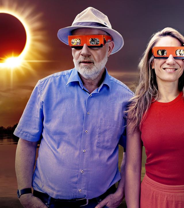 Ein Mann mit Hut und eine Frau stehen vor einer Sonnenfinsternis