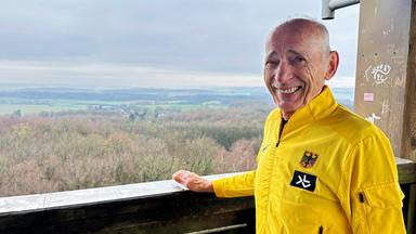 Ein Mann schaut lachend mit gelber Sportjacke zur Kamera