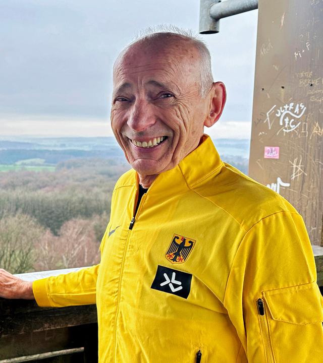 Ein Mann schaut lachend mit gelber Sportjacke zur Kamera