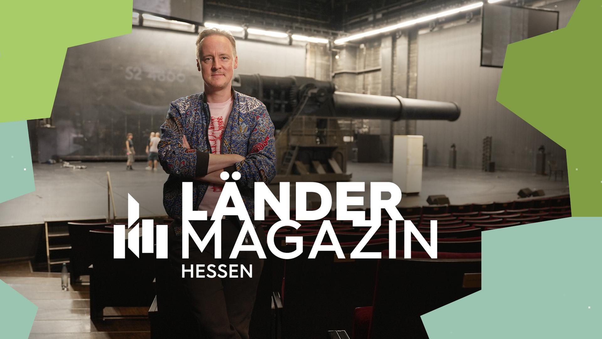 Theaterregisseur Jan-Christoph Gockel im Theatersaal vor der Bühne auf der eine Kanone aufgebaut ist.