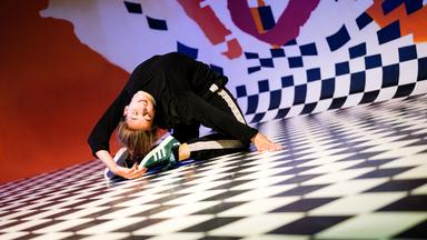 Momentaufnahme: Frau auf dem Boden bei akrobatischer Rückwärtsbeuge.