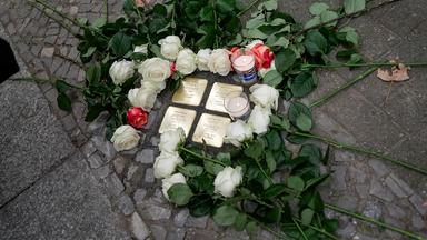 Stolpersteine am Boden eingerahmt von Rosen.