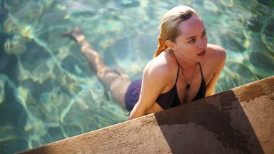 Penelope (Dakota Johnson) stützt sich am Pool-Rand ab und schaut verführerisch nach oben.