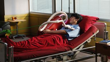 Mann liegt mit Staubsauger in einem Bett