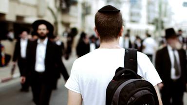 Junger Mann von hinten gezeigt, der durch das orthodoxe Jerusalem spaziert.