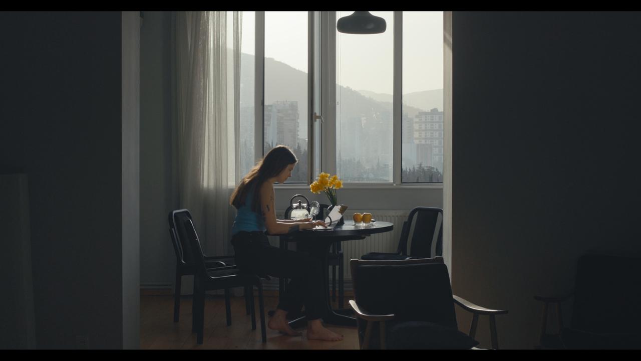 Junge Frau am Tisch mit Blumen.