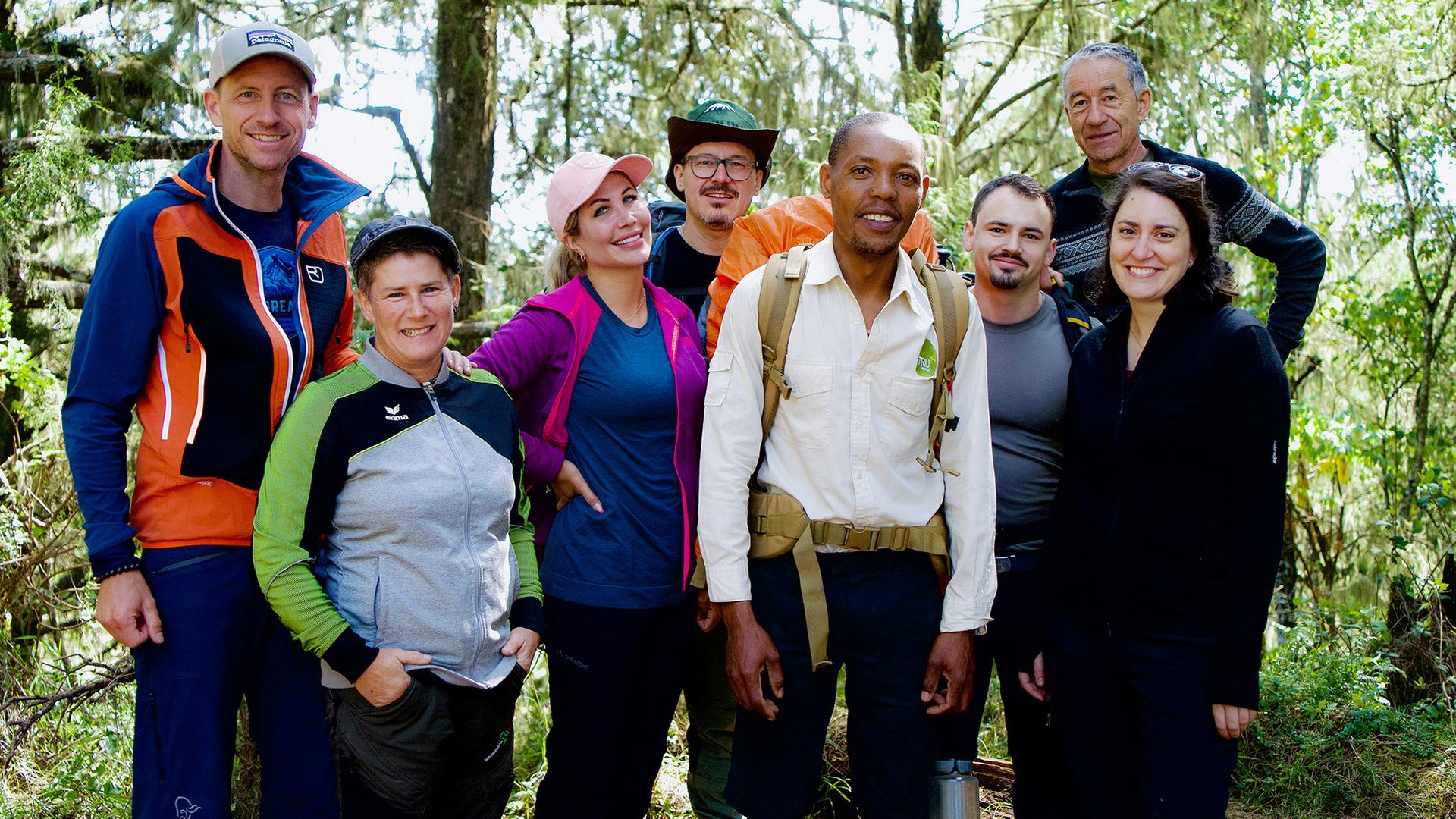 Acht Personen in Trekkingausrüstung posieren für ein Gruppenbild