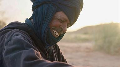 Ein Beduine in traditioneller Kleidung lacht.