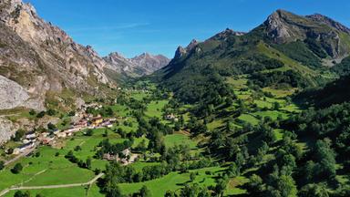 Blick auf Dörfer zwischen grünen Wiesen, Wäldern und Bergen vor tiefblauem Himmel