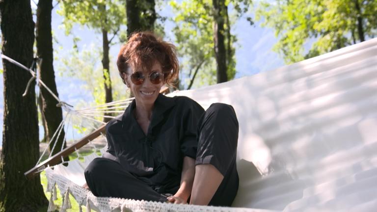 Sybille Berg sitzend in einer Hängematte.