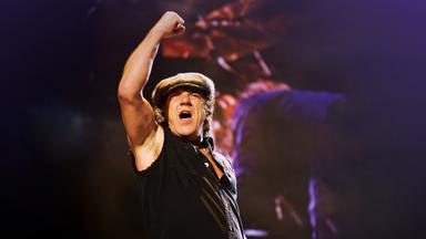 Bryan Johnson streckt auf der Bühne die rechte Faust in die Luft.