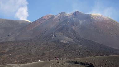 "ÄTNA - Höllenschlund im Mittelmeer": Der Ätna mit einer Rauchfahne an der Spitze, im Vordergrund sind Wanderer zu sehen.
