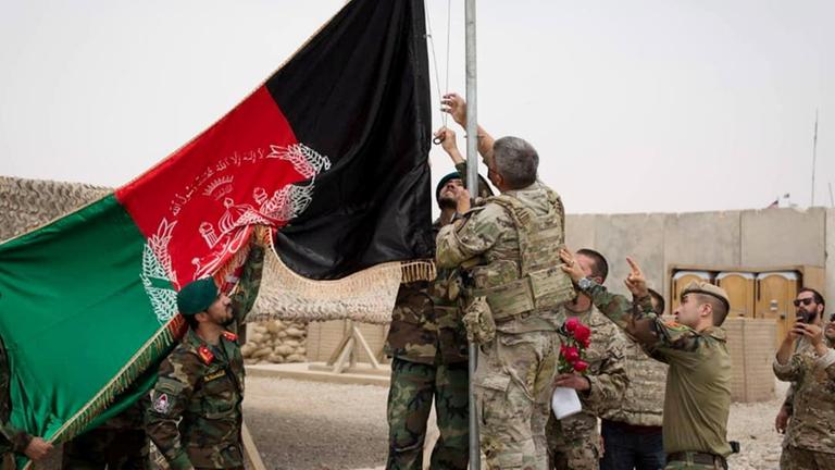 Soldaten hantieren an einem Flaggenmast mit einer Flagge, die die afghanischen Farben zeigt.