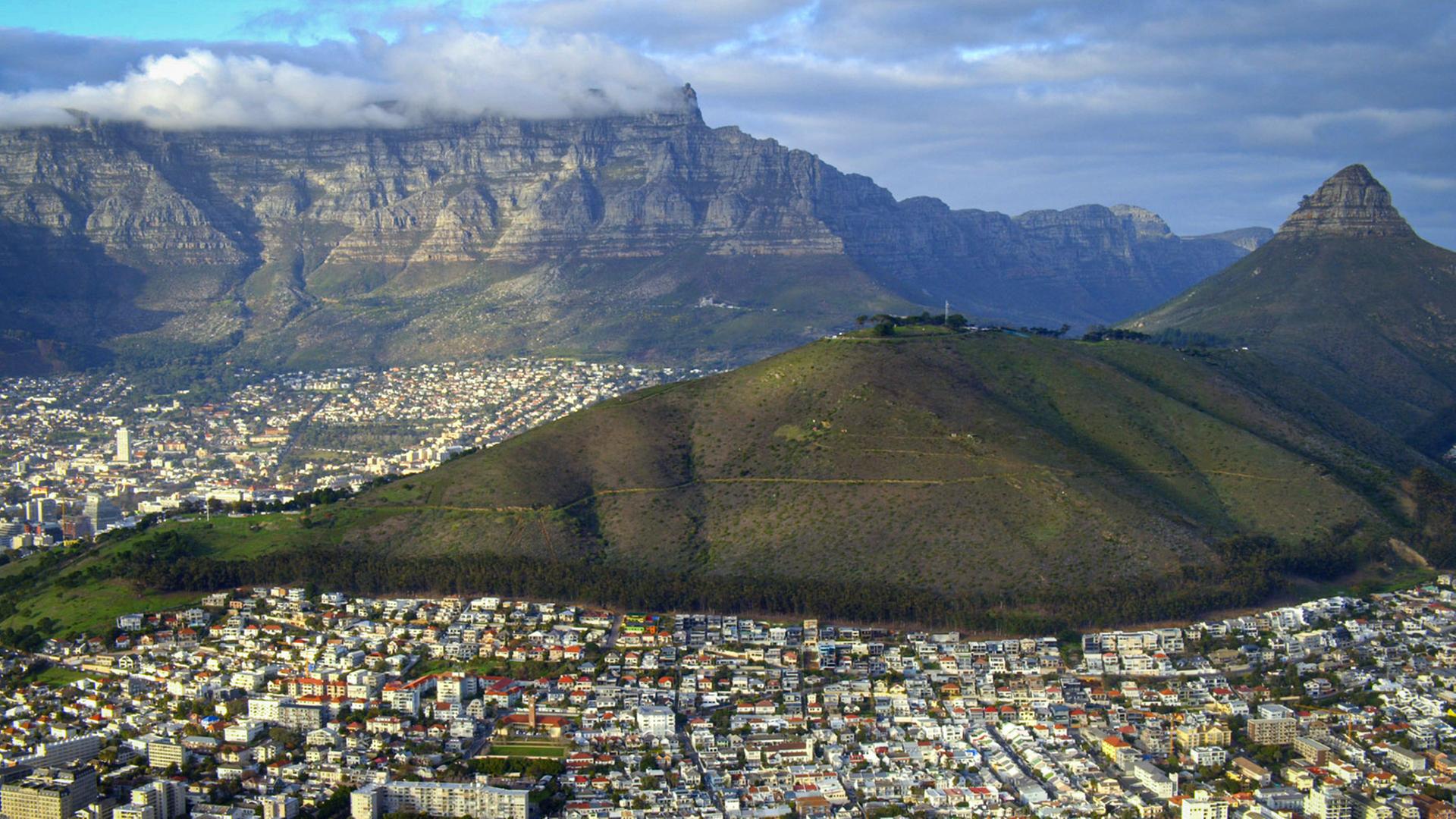 Siedlungen umrunden einen Berg. Im Hintergrund Gebirge.