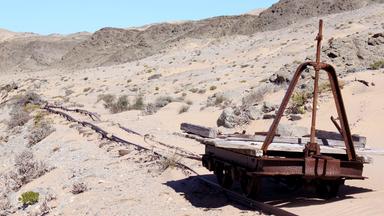 Alte Eisenbahnschienen mit einem verrosteten Schienenfahrzeug