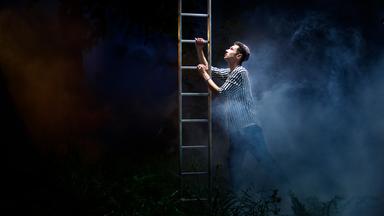 Lars steigt im Nebel eine Leiter hinauf. Er trägt dabei seine Kippa.