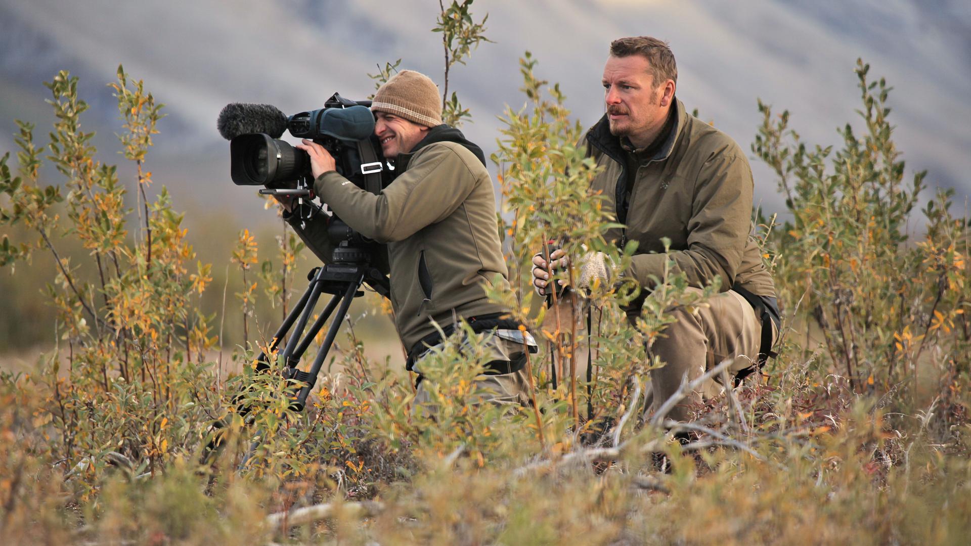 Zwei Männer mit einer großen Kamera in der Wildnis.