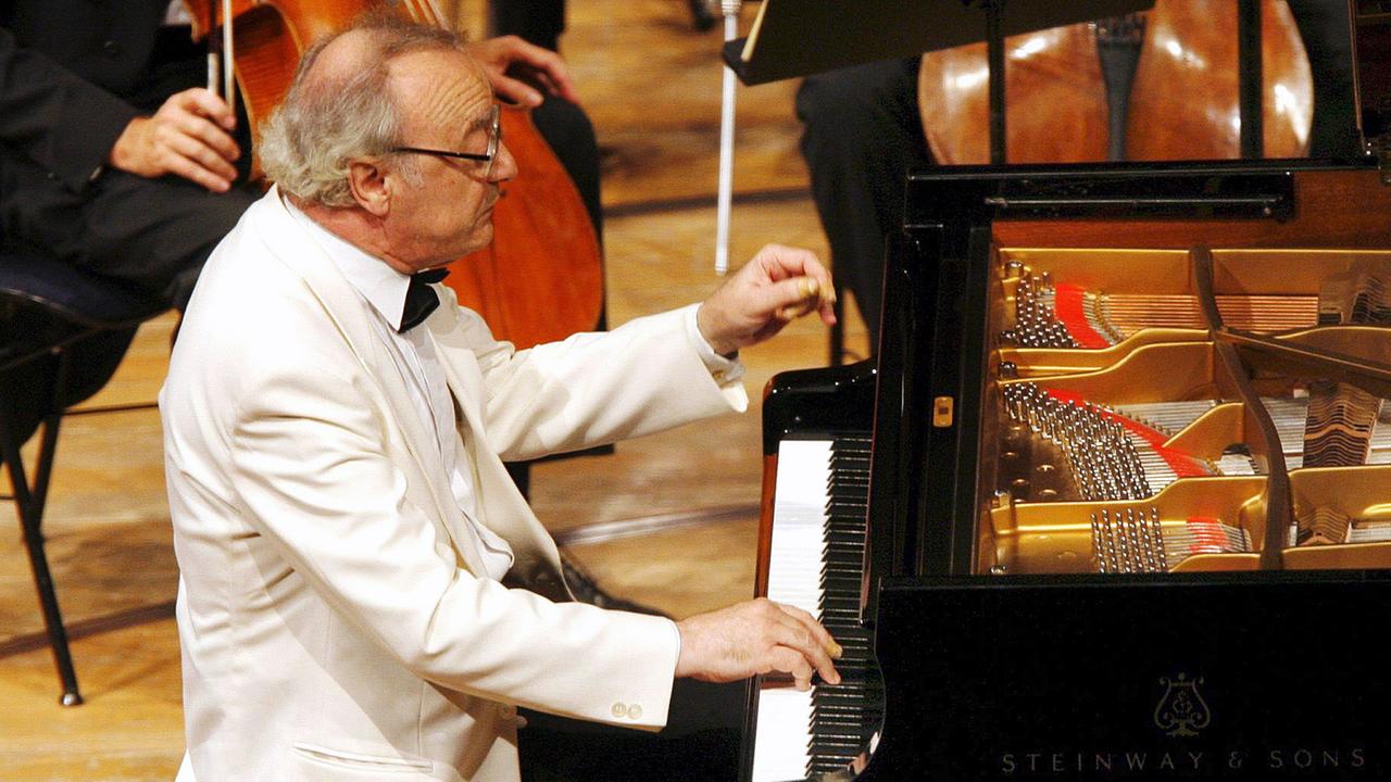 Mann sitzt an Flügel und spielt auf einer Bühne